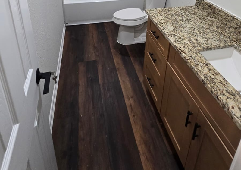 Bathroom with granite countertop and wood flooring.